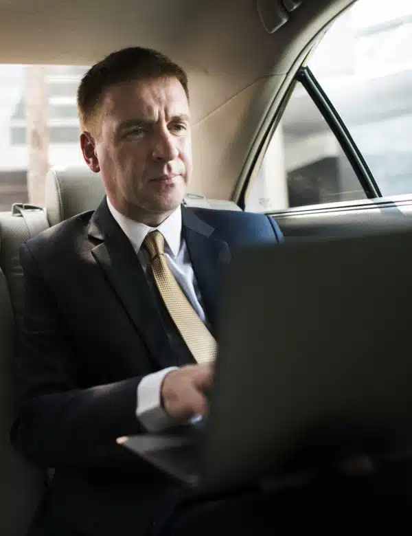 Business traveler using laptop in luxury private car during executive ride in Charlotte