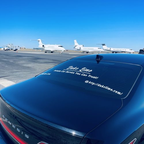 Duke Limo black sedan at private airport with jets in background – executive car service in Concord NC
