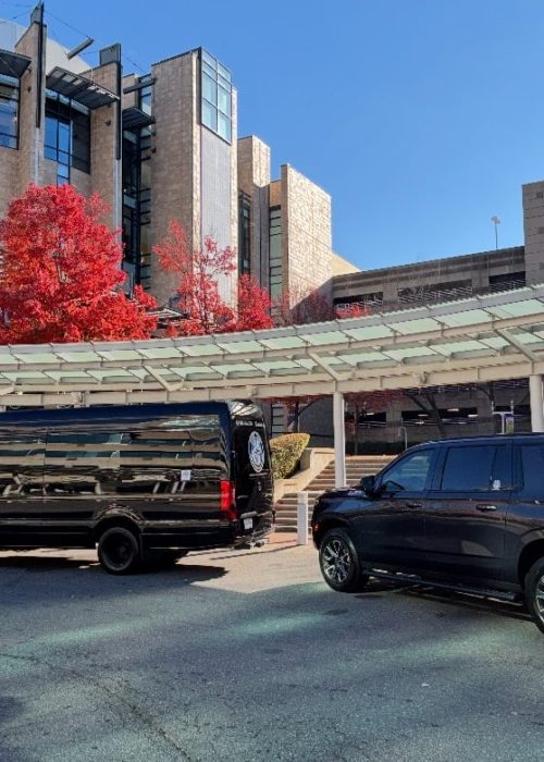 Luxury Sprinter van and black SUV from Duke Limo parked at Atrium Health medical center in Charlotte, NC, for Limo service.